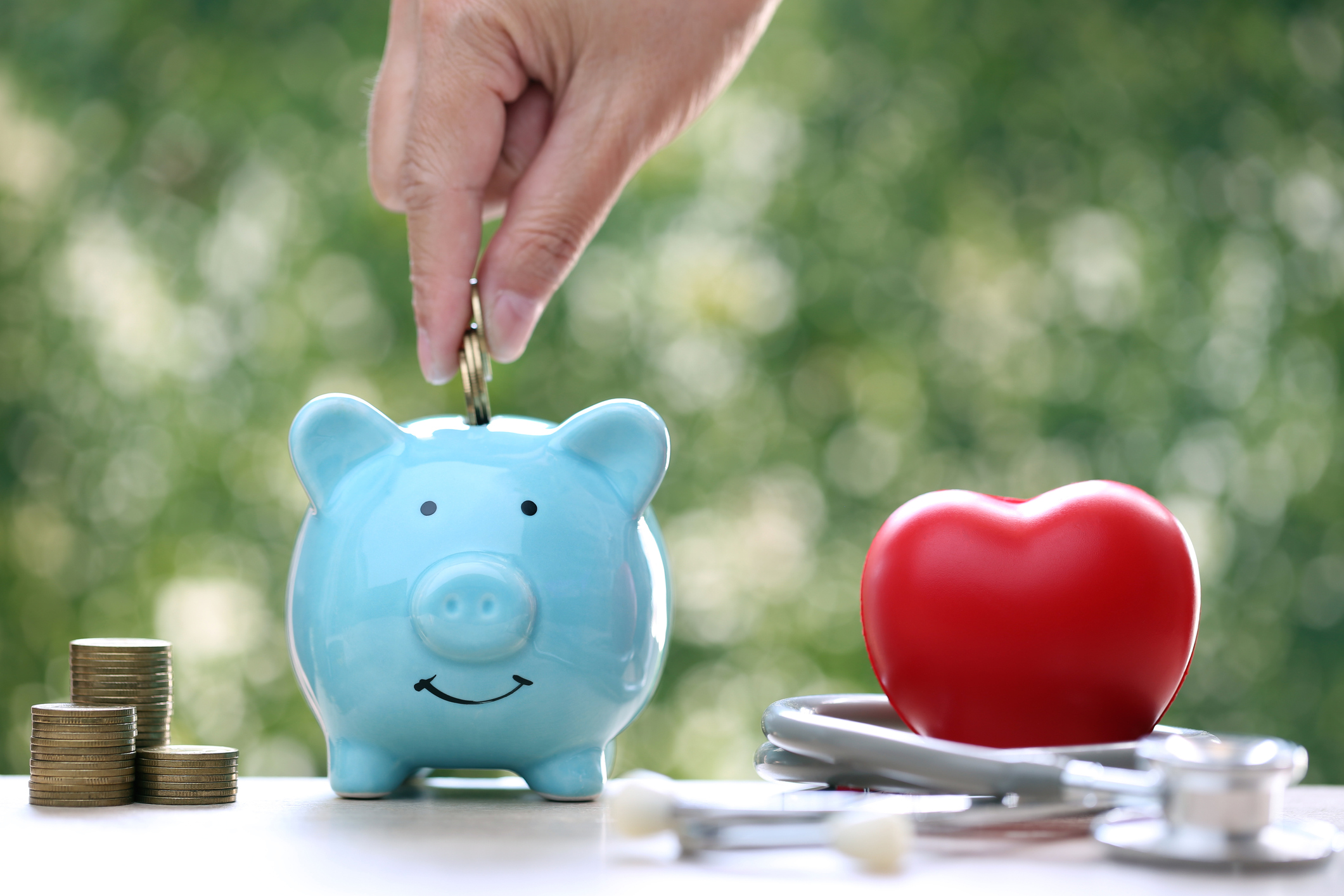 Piggy bank with stethoscope and red heart on green